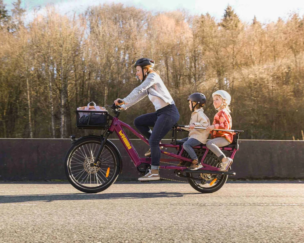 Maman et deux enfants sur un vélo cargo électrique Yuba