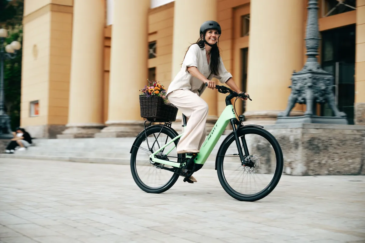 Cycliste souriante sur un vélo électrique urbain Scott Passage en ville